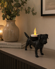 Zwarte Waxinelichthouder Border Terrier met led-waxinelichtje op een kastje langs de wand in moderne warme woonomgeving met decoratieve accessoires.